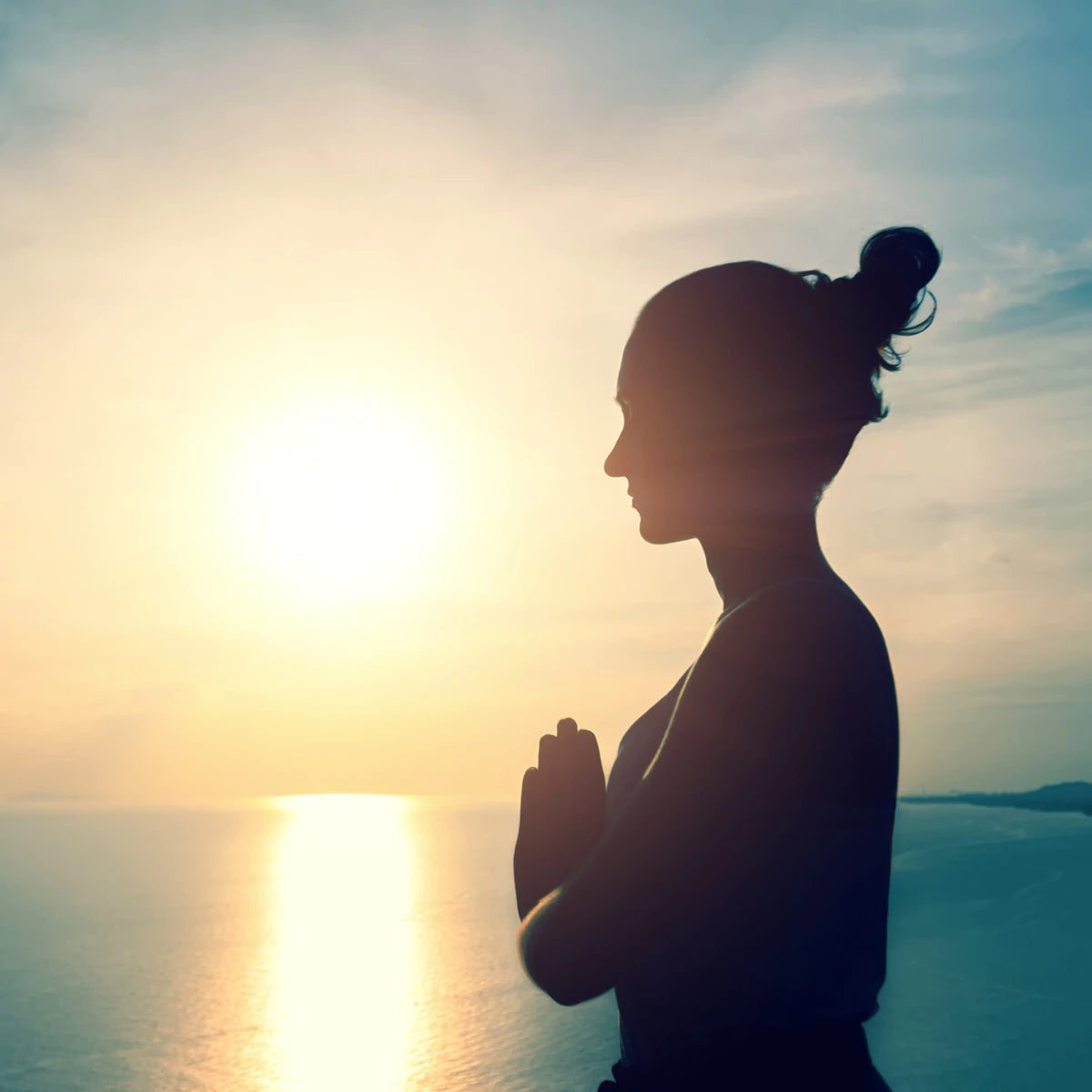 Lady at sunset practicing yoga with hands in a prayer position, anjali mudra