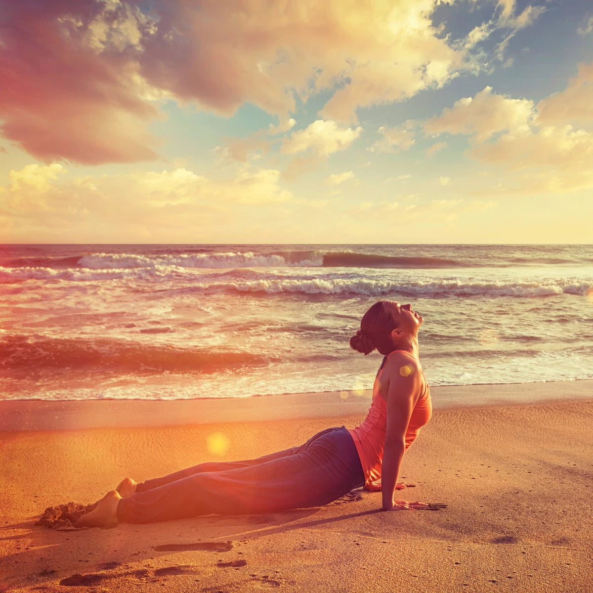 Lady practicing yoga on the beach doing the yoga pose upward facing dog