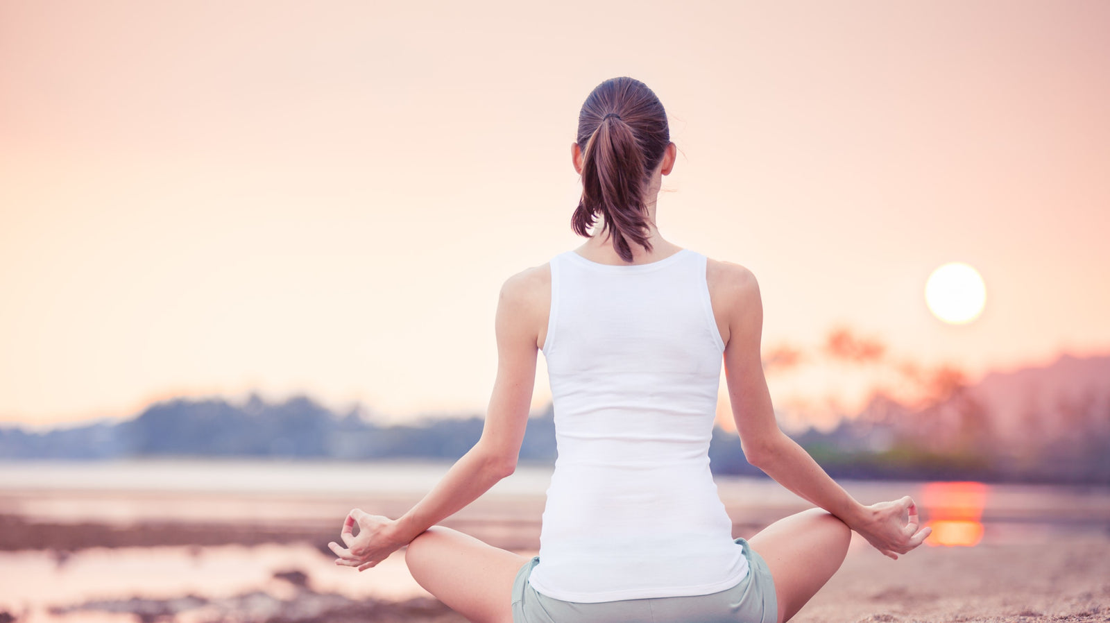 Attractive lady meditating at sunset