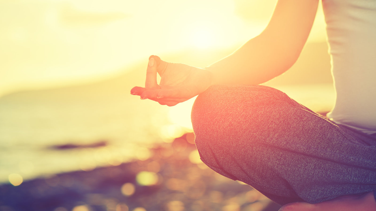 Person meditating at sunset