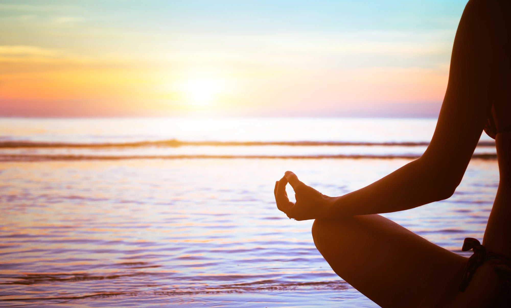 Person meditating at sunset