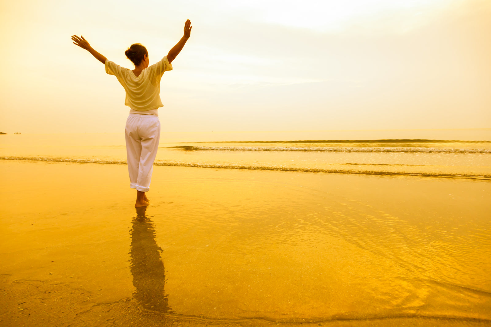 Lady at the beach during sunset lifting arms