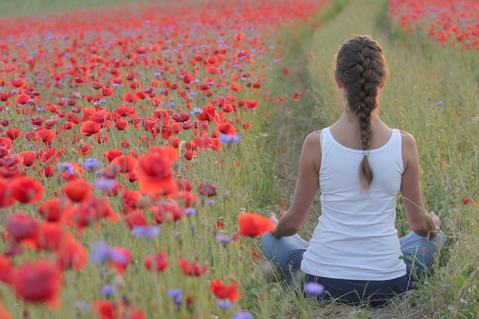Lady practicing yoga in a poppy field
