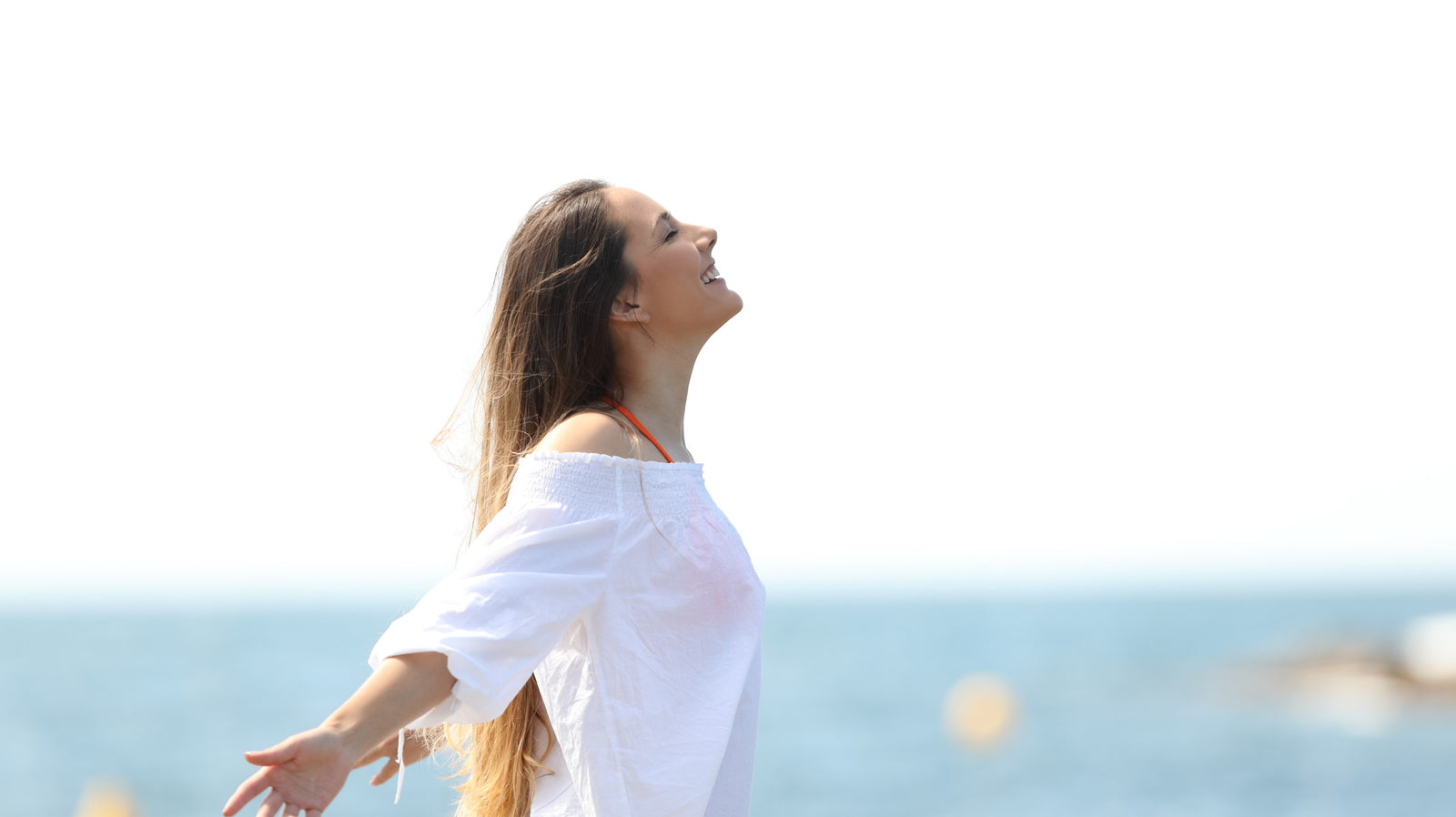 young woman opening her arms at the beach