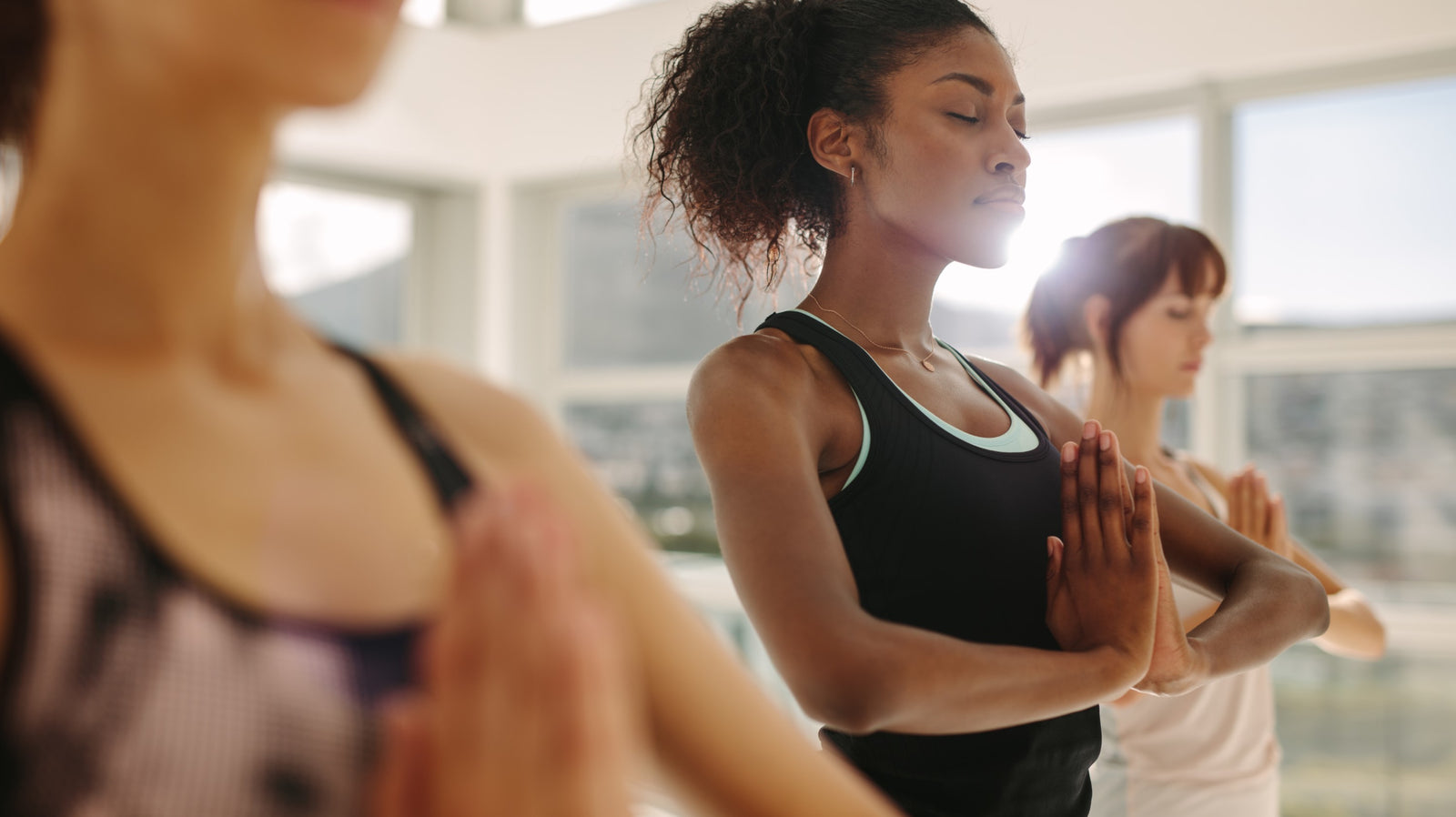 Yoga Class Standing in Tadasana the mountain with hands in Anjali Mudra, Prayer Position or Namaste