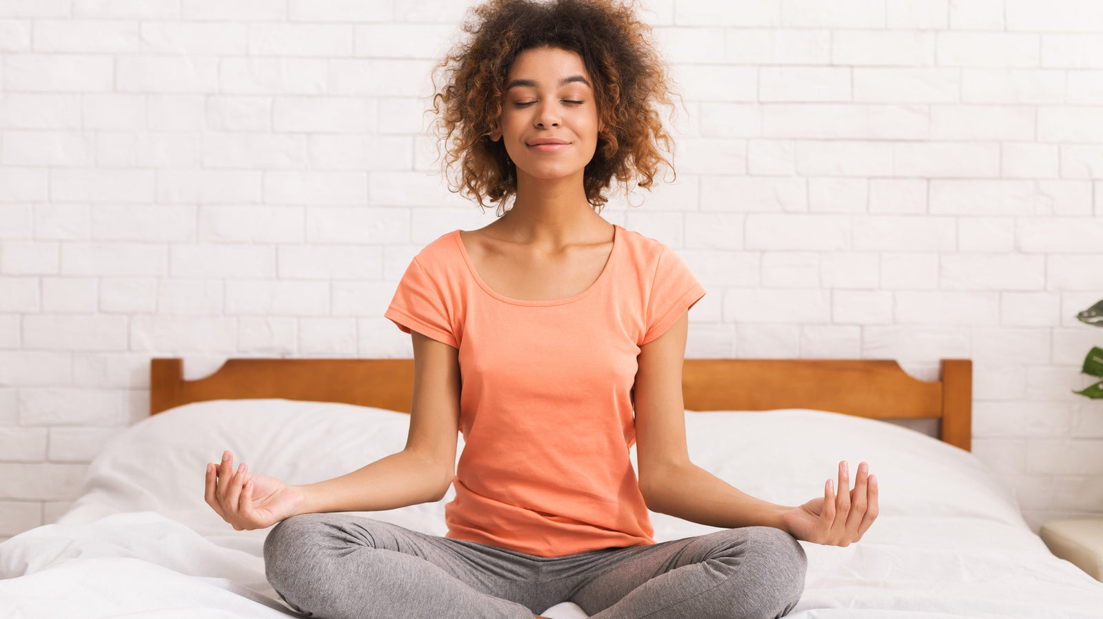 Lady sitting meditating on a bed